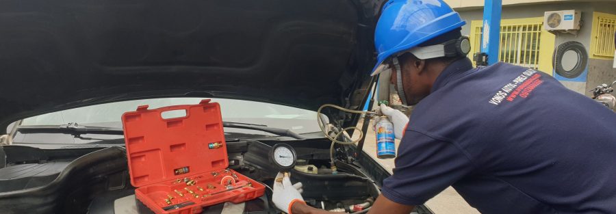 A technician performing an air conditioning refrigerant refill on a car. The technician is connecting a hose to the car's AC system to replenish refrigerant, addressing a common car AC problem and providing a solution for improved cooling performance.